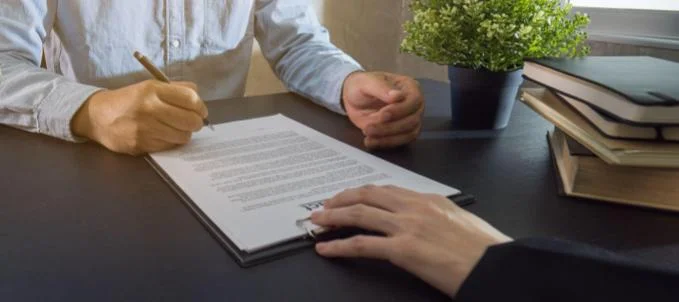 Como comprovar regularidade fiscal? Na imagem, homem assinando documento em representação a comprovação de regularidade para licitação
