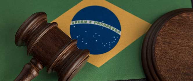 nova-lei-de-licitações-14133 Quais os critérios de julgamento da Lei 14133? Na imagem, martelo da justiça sobre a bandeira do Brasil em alusão ao tema que trata sobre quantos e quais são os critérios de julgamento na proposta licitatória.